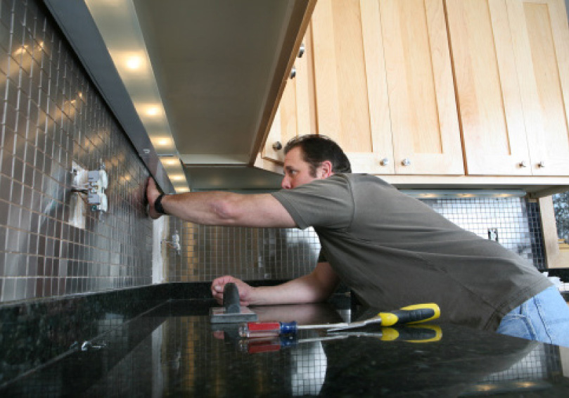 man working on kitchen backsplash tiles